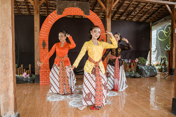 Fototapeta na wymiar portrait of three young women presenting traditional Javanese dance movements in traditional javanese joglo house