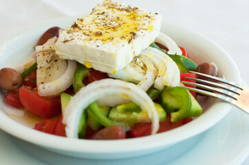 Classic Greek salad from tomatoes, cucumbers, red pepper, onion with olives, oregano and feta cheese.