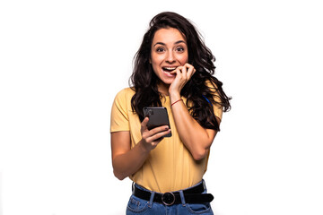 Fototapeta premium Portrait of a shocked woman using mobile phone isolated over white background