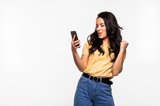 Portrait Of A Happy Joyful Woman Holding Mobile Phone And Celebrating A Win Isolated Over White Background