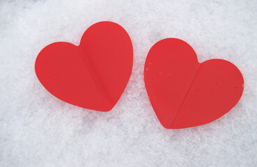 Fototapeta premium Two beautiful romantic red hearts together on a white snowy background. The concept of love and Valentine's Day