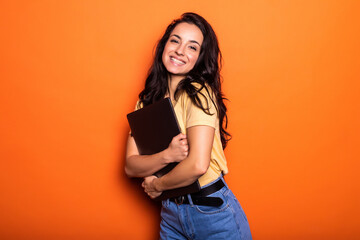 Smiling young blonde woman holding laptop posing isolated on yellow orange background. People...