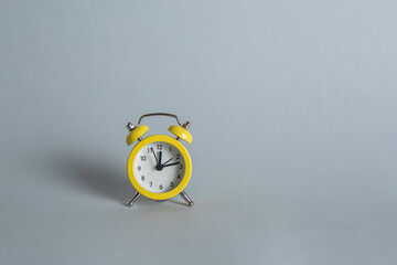 Yellow small alarm clock on a gray background with empty space for text. Minimalistic banner with colors of the year 2021 - Illuminating and Ultimate Gray. - 398375646