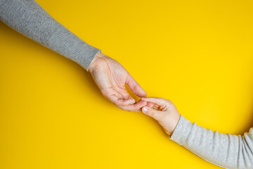 Mom and child in gray clothes holding hands on yellow background. Creative banner with two colors of the year 2021 - Illuminating and Ultimate Gray.