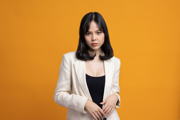 Obraz premium Attractive Beautiful asian woman standing and posing. Sexy female in suit on isolated yellow background.