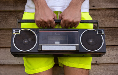 Man wearing yellow pants holding an old radio