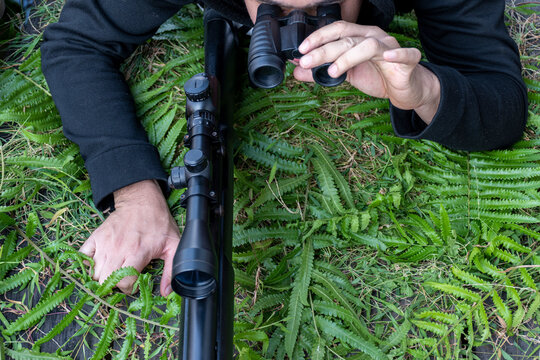 Top view man with a binoculars and rifle on grass floor