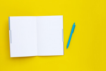 Notebook with pen on yellow background.