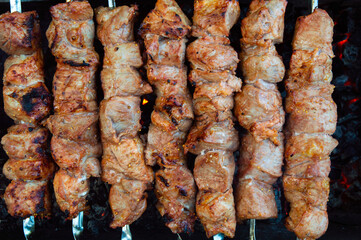 pork kebab on skewers is grilled over charcoal, smoke over a barbecue, the last degree of cooking, close