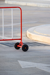 Part of the red traffic barrier with white arrow sign on street surface in entrance way area
