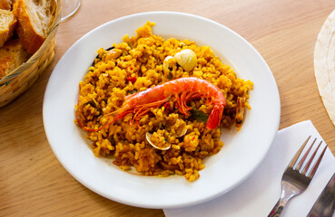 Traditional Valencian paella de mariscos with shrimps and mussels served on white plate