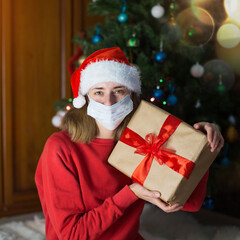Fototapeta na wymiar girl in red clothes and medical mask unfold New year gifts. the concept of celebrating Christmas midnight. Holiday's decor boce, Christmas tree