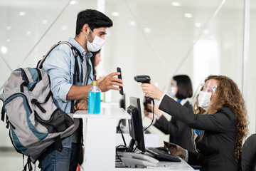 Caucasian male passenger handing phone to staff for check-in scanning.