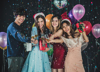 Happy Young friends celebrating Christmas or New Year eve at night and Having joyful moment. Balloons and lights decorating background, selective focus