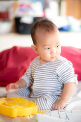 Asian infant baby sitting and playin on the bed after wake up in the morning