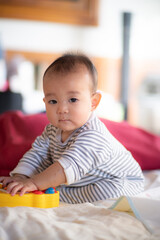 Asian infant baby sitting and playin on the bed after wake up in the morning