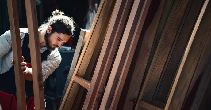 carpenter in wood workshop selecting wooden frame for his workwood