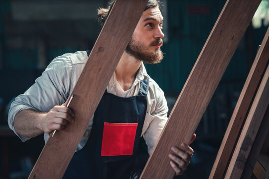 carpenter in wood workshop selecting wooden frame for his workwood