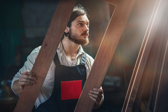 carpenter in wood workshop selecting wooden frame for his workwood