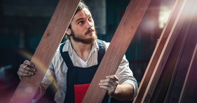 carpenter in wood workshop selecting wooden frame for his workwood