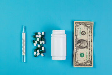 Tablets, pills, white bottle and dollar bill on a blue background. Top view. Space for text. Pharmacology and medicine struggle for health. Treatment and prevention of viral diseases.