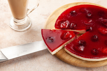 Homemade cherry and strawberry cheesecake, latte macchiato cup, cut piece of pie on knife