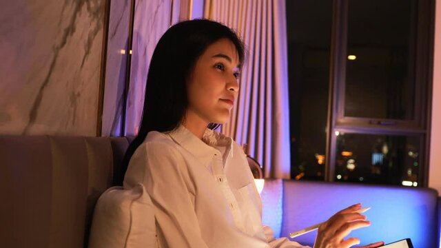 Young Asian beautiful sexy woman  using smartphone- tablet  enjoy  social online and facetime and listening music on bed with happy and smile in bedroom at night time.