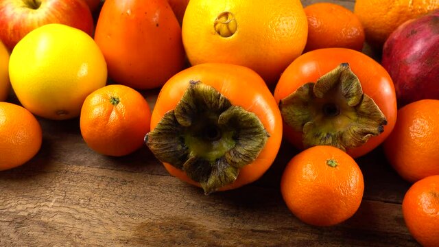 Tangerines, lemons, persimmons, oranges, apple and pomegranates on an old wooden vintage board.