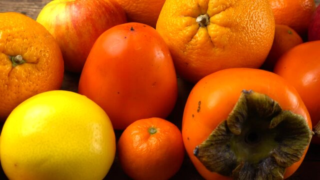 Tangerines, lemons, persimmons, oranges, apple and pomegranates on an old wooden vintage board.