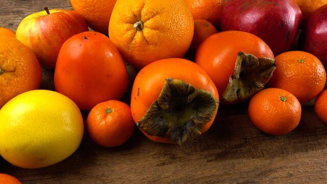 Tangerines, lemons, persimmons, oranges, apple and pomegranates on an old wooden vintage board.
