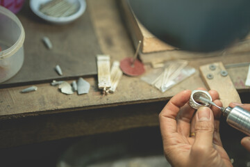 Jeweler at work in jewelry. Desktop for craft jewelry making with professional tools. Close up view of tools. Silver ring.