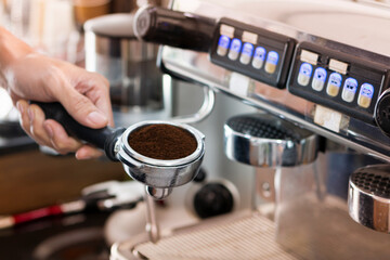 Young male Bartender in cafe restaurant. Smiling young waitress or small cafe business owner entrepreneur looking at camera, wear apron posing in restaurant coffeeshop. Barista making cappuccino.