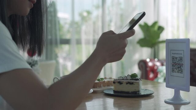 Women's hands are using  the phone to scan the qr code to select food menu. Scan to get discounts or pay for food. The concept of using a phone to transfer money or paying money online without cash.