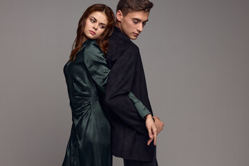 A sexy woman in a dress and a man in a suit stand with their backs to each other