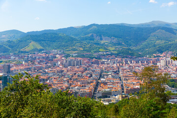 Obraz premium Scenic panoramic view of modern Bilbao cityscape surrounded by mountain ranges in summer, Spain ..