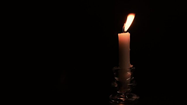 Candlestick holder with burning candle flame on black background, copy space, 4K