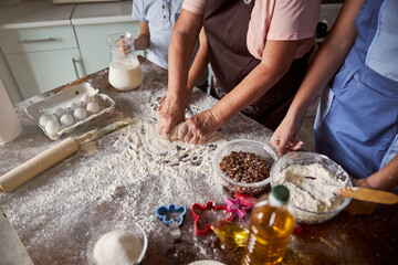 Obraz na płótnie Canvas Senior lady preparing dough for baking with her children