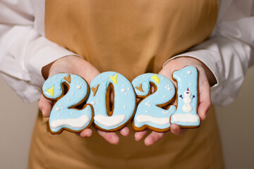 Pastry chef holds Christmas gingerbread in the form of 2021 numbers. New Year concept.
