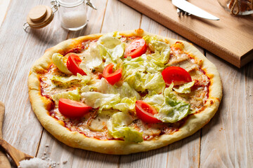 Side view on chicken caesar pizza with tomatoes and lettuce