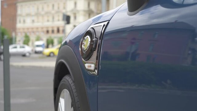 Modern businessman charges her electric car in the city.