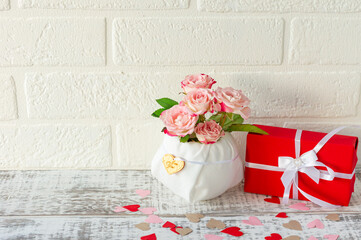 Festive greeting card for holidays. Beautiful bouquet of pink roses and gift box on wooden background.