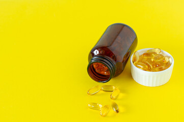 Fish oil capsules on yellow background, vitamin D, omega supplement, selective focus.