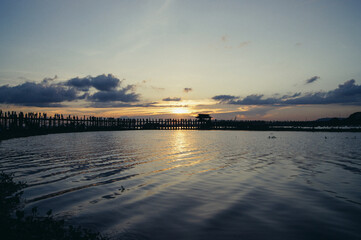 a body of water with a dock and a sunset in the background