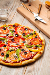 Closeup on vegetable pizza with olives and pepper on the wooden table