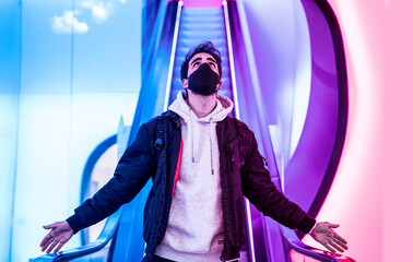 Shot of a man in a medical mask standing on  an escalator