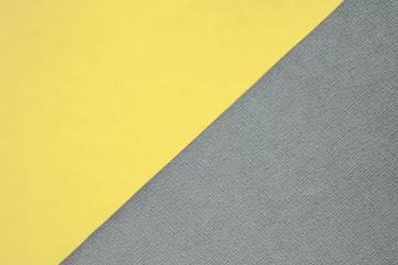 Strukturierte und normale Papierblätter, die diagonal geteilt werden, wodurch eine Linientrennung entsteht. Trendiges pastellfarbenes gelbes und neutrales graues abstraktes Duo-Ton-Hintergrunddesign. Jahresfarbkonzept © Aleksandra Konoplya