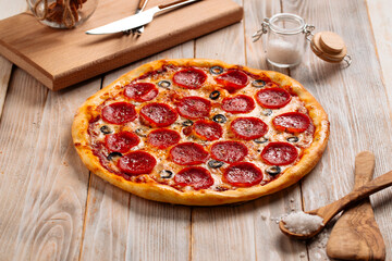 Fresh baked pepperoni pizza with salami and olives on the wooden table
