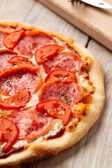 Closeup on ham pizza with tomato with dried herbs on the wooden table
