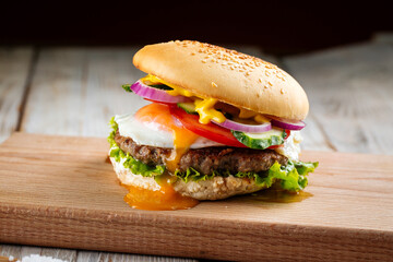 Side view on classic burger with egg on the wooden board