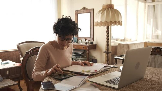 Home office working environment. Using laptop and working efficiently. Using technology and working at home productively. Young female adult study focused.